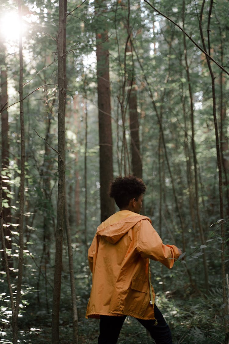 Teenage Boy In Yellow Raincoat Walking In Forest