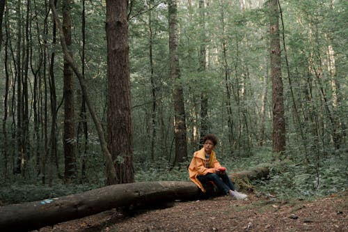 Sad Teenage Boy in Yellow raincoat Sitting in Forest