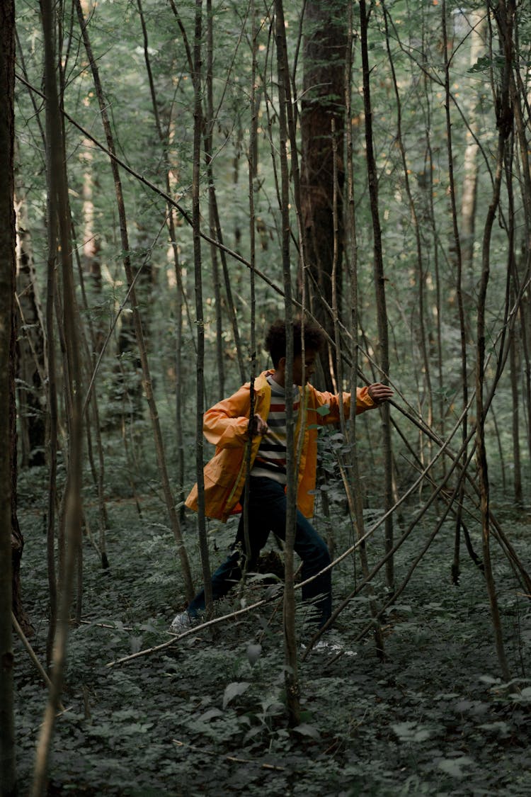 Teenage Boy In Yellow Raincoat Running In Forest