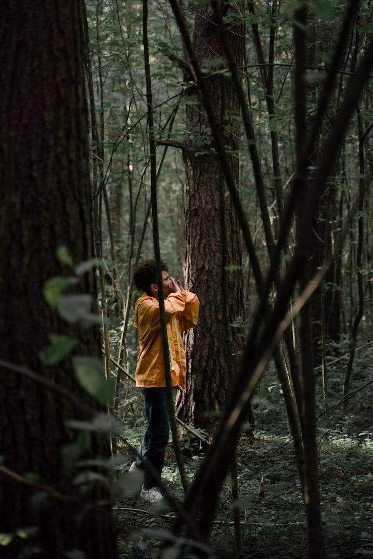 Teenage Boy In Yellow Raincoat Shouting In Forest