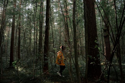 Teenage Boy in Yellow Raincoat Walking in Forest
