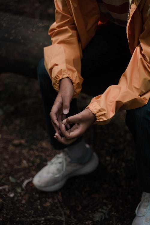 Close-up of Hands of Teenage Boy in Yellow Raincoat in Forest