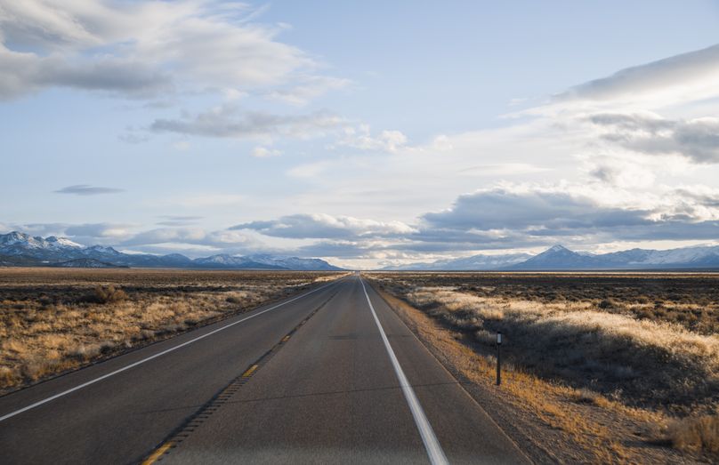 Endless desert road with mountain view under a clouded sky — photo by John De Leon on Pexels