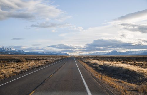 Free Endless Nevada road with mountain view and vast grassland under a cloudy sky. Stock Photo