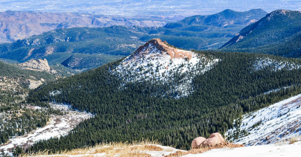 Stunning view of Pikes Peak with snow and lush green forests in El Paso County, Colorado.