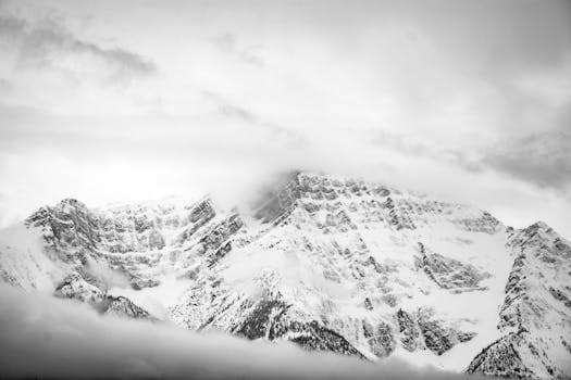 Breathtaking monochrome view of snow-covered Canadian mountains beneath a cloudy sky.