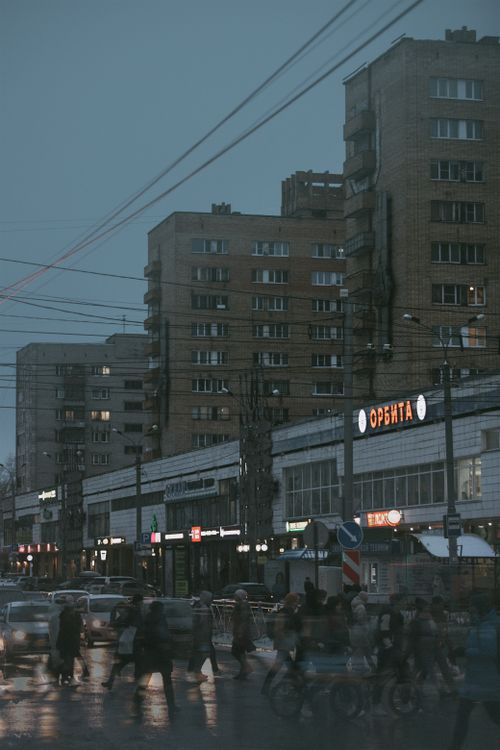 Free Vibrant city street scene at dusk with high-rise buildings and pedestrians crossing. Stock Photo