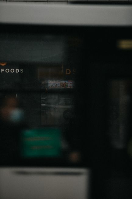 Blurred urban setting with window reflections and street kiosk at night.