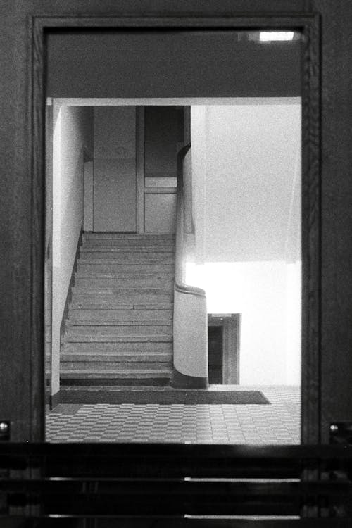 Grayscale Photo of Staircase In Front of Mirror