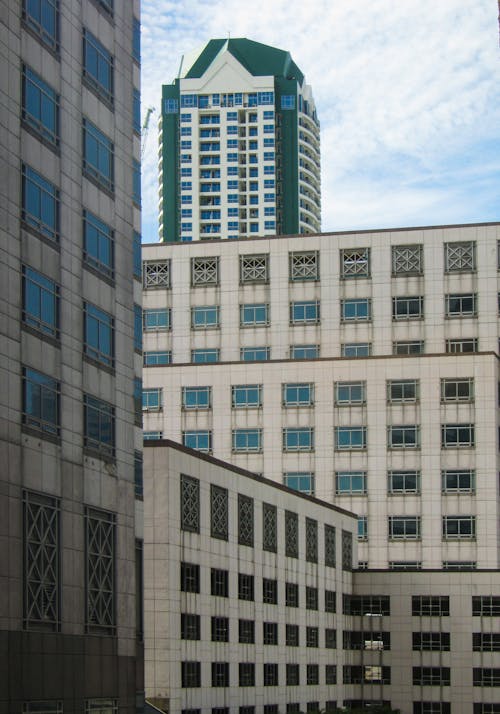 A Green and White High Rise Building Behind a White Building