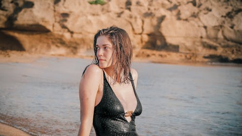 Woman in Black Swimsuit Sitting Beside Body of Water 