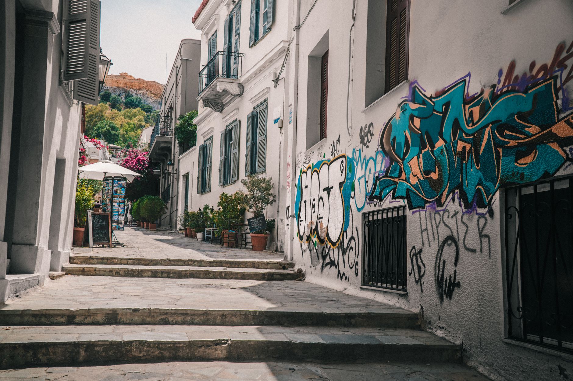 Picturesque European alleyway with urban art and a parked scooter under clear skies.