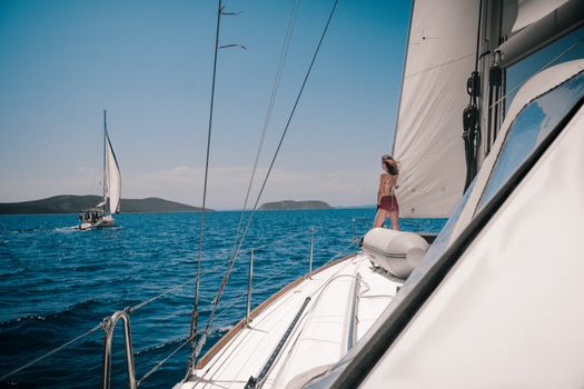 Woman standing on yacht deck sailing through the Aegean Sea near Athens, Greece.