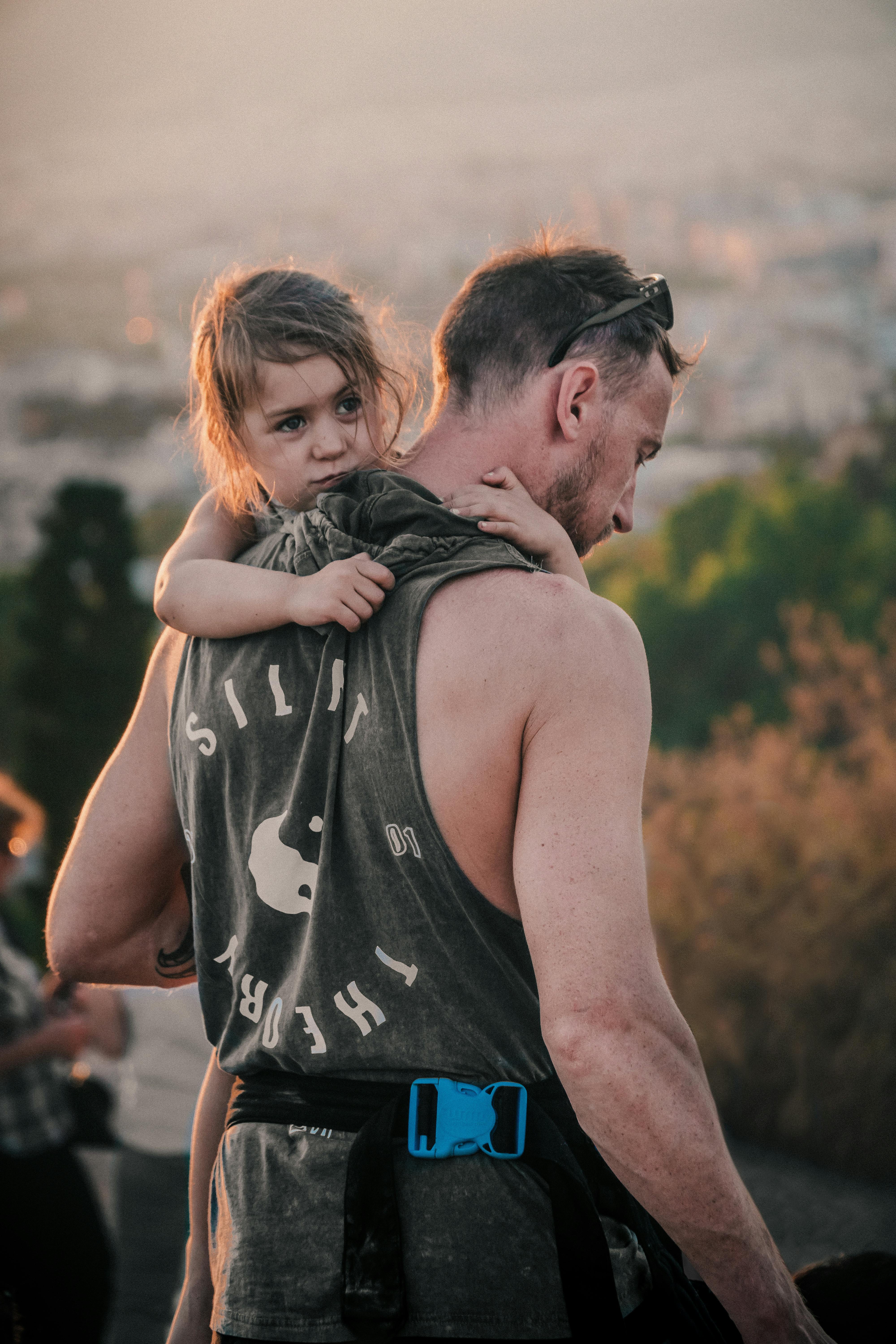 a man in black tank top carrying a girl