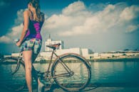 一名妇女在明亮多云的天空下，沿着河边骑自行车休息，非常适合休闲和探索