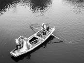 黑白照片中，渔民在一条宁静的河流上撒网