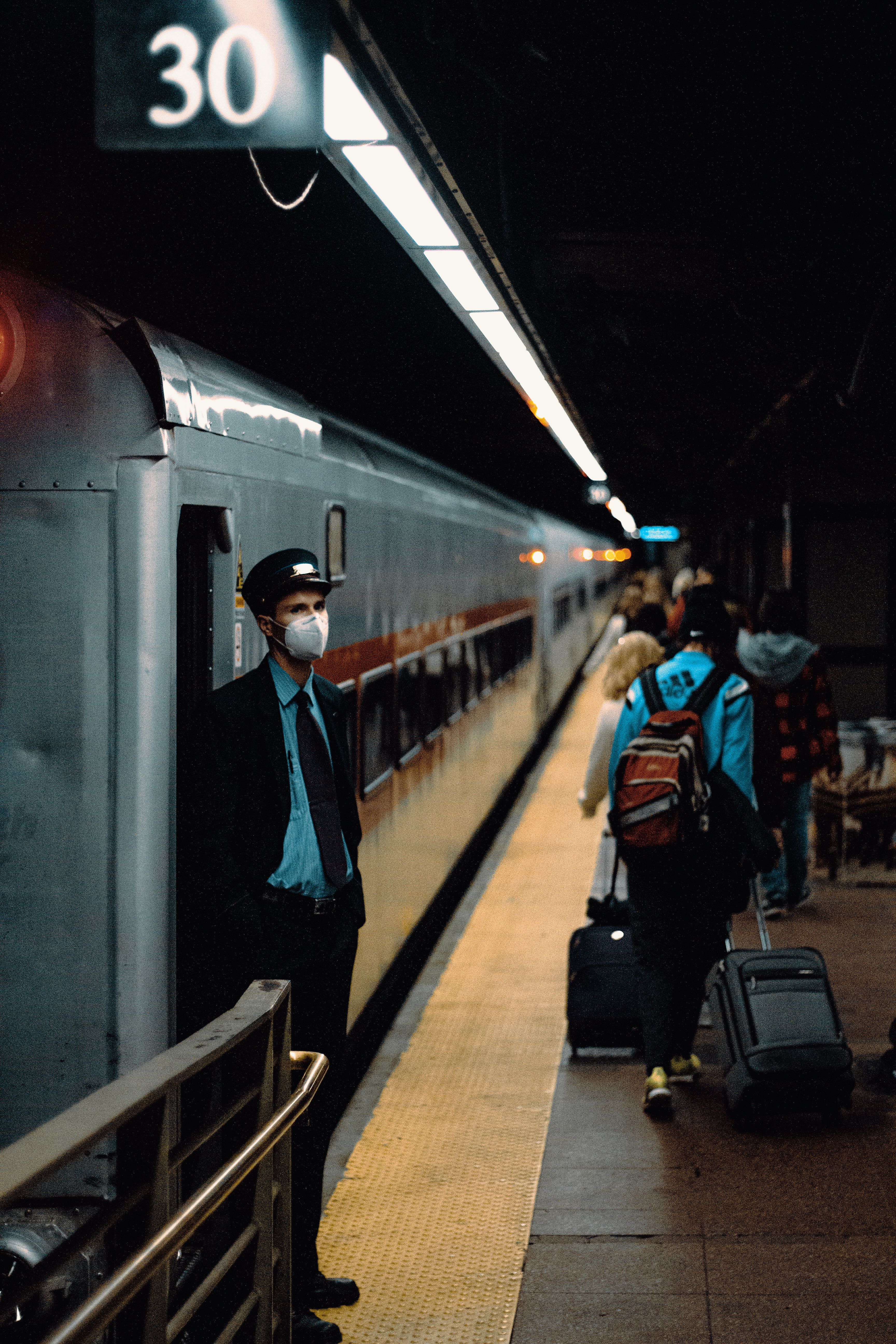 A Man in Black Jacket Wearing Face Mask Standing Beside Train · Free ...