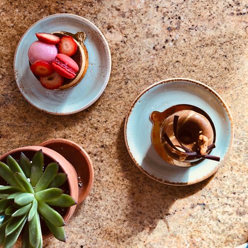 Free Top view of gourmet desserts with strawberries and macarons on a granite countertop, featuring a succulent. Stock Photo