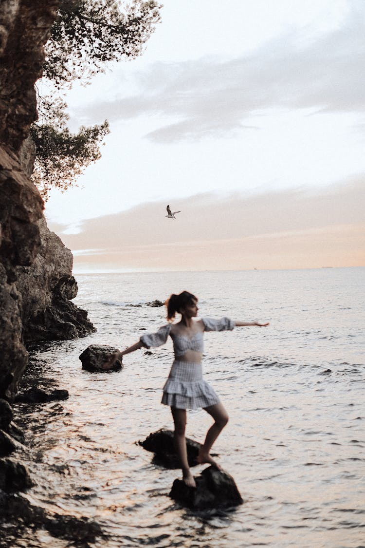 Woman Standing On Rocks In Water