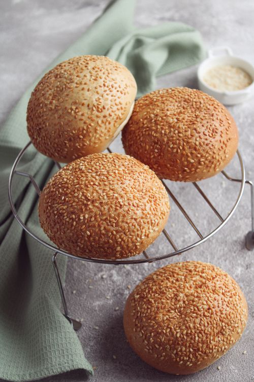 Free Delicious sesame seed buns cooling on a rack with a rustic background. Stock Photo