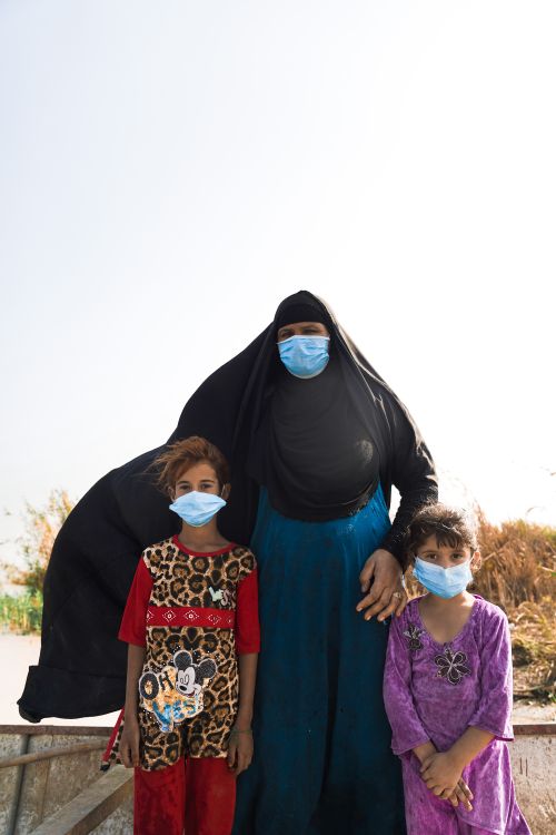 Free A mother with her two young daughters wearing face masks outdoors on a sunny day. Stock Photo