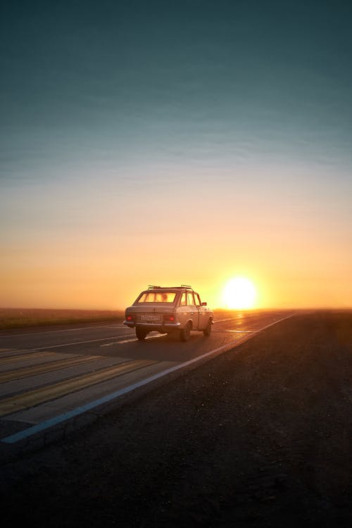 A Car Traveling on the Road During Sunset