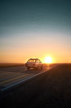A retro vehicle travels down a rural road as the sun sets in Kueda, Perm Krai, Russia.