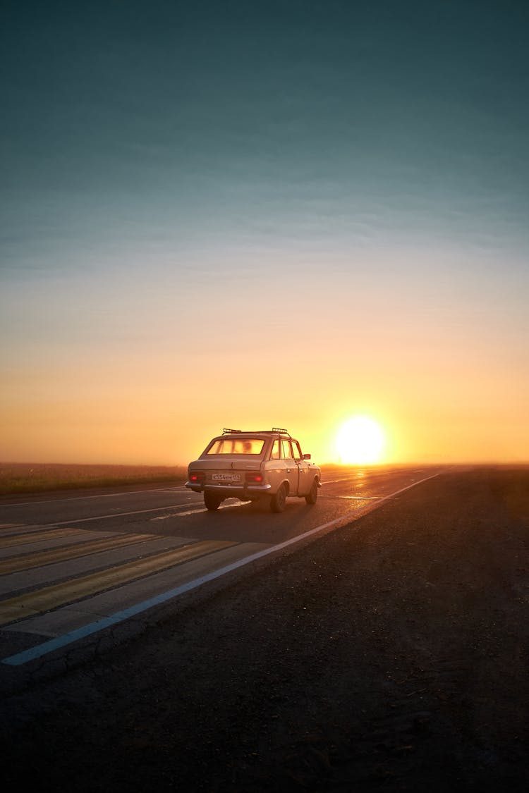 A Car Traveling On The Road During Sunset