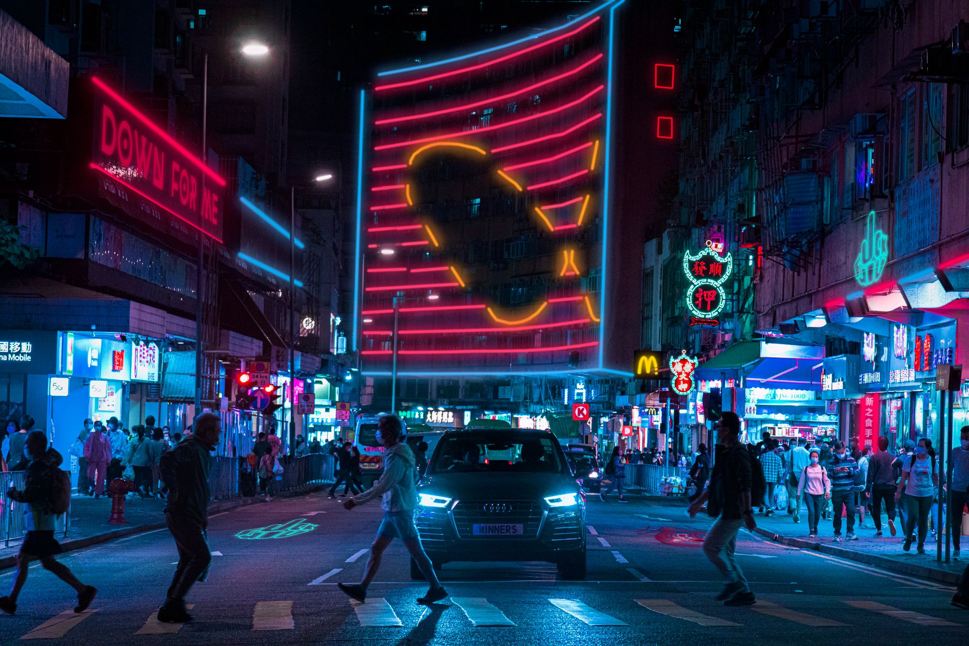 A bustling night street scene in Hong Kong with neon lights and pedestrians crossing.