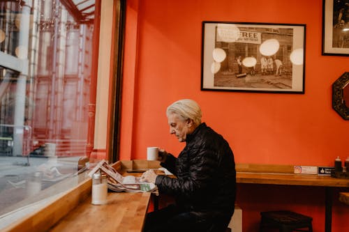Free Elderly Man Sitting in Cafe Reading Newspaper Stock Photo