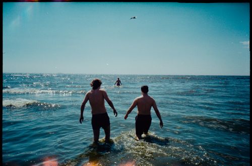 Free Two men walking into the sea on a sunny day, capturing the essence of summer fun. Stock Photo