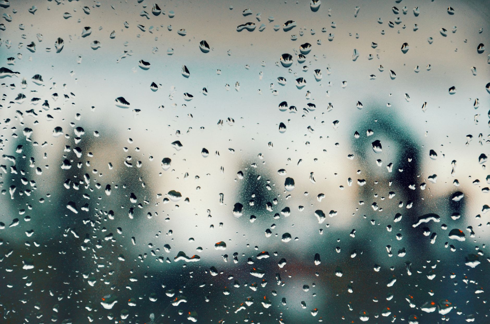 Close-up of water droplets on a window with a blurred background view.