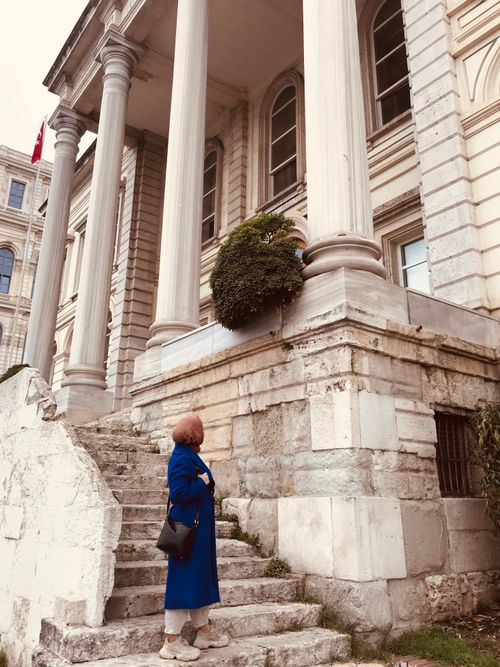 Free A woman in a blue coat stands on stairs outside a historic building in Istanbul, Turkey. Stock Photo