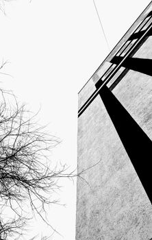 Low-angle black-and-white shot of a concrete building facade with dramatic shadows.