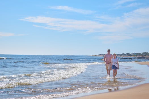 A couple walking along the sandy beach of Piriápolis, Uruguay, on a sunny day by the seaside.