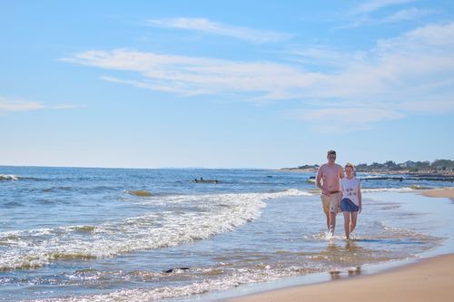 Free A couple walking along the sandy beach of Piriápolis, Uruguay, on a sunny day by the seaside. Stock Photo