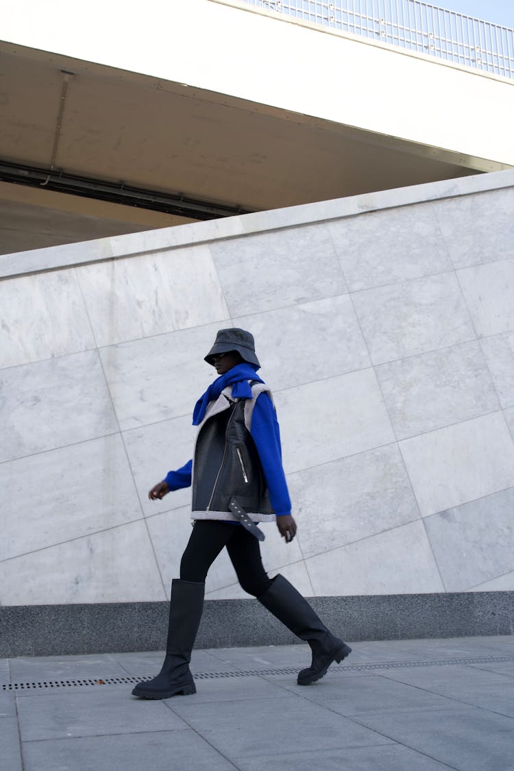 Unrecognizable Person In Big Boots Walking Along Concrete Urban Structure