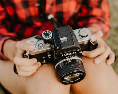 Free Hands holding a vintage Nikon camera, showcasing photography passion outdoors. Stock Photo