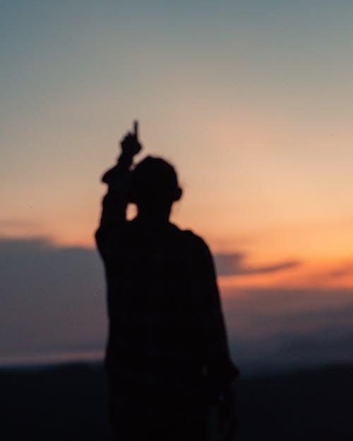 Blurred Silhouette of a Person Pointing Upward