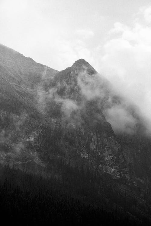 Grayscale Photo of Mountain Surrounded With Clouds 