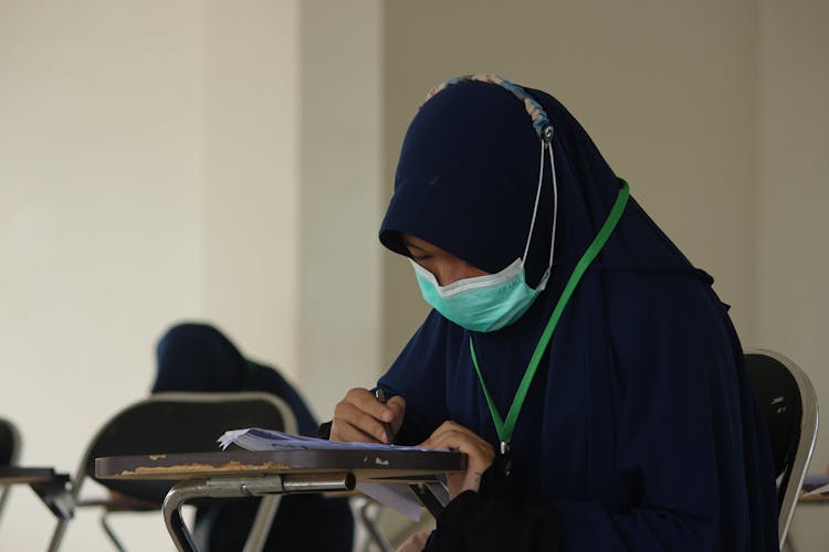 Woman In Black Hijab Sitting On Chair Writing