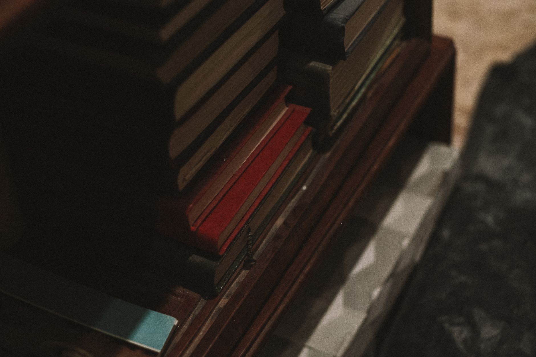 A dark, moody image of a stack of books on a wooden shelf, evoking a vintage feel.