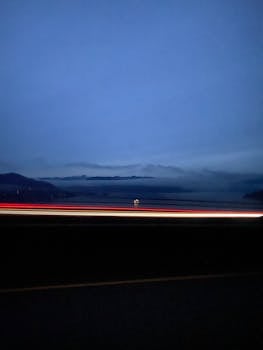 A serene ocean view at dusk with dynamic light trails and a calm horizon.