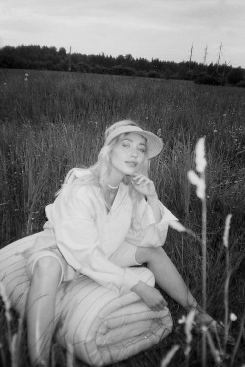 Free Grayscale Photo of a Woman Posing on the Grass Field Stock Photo