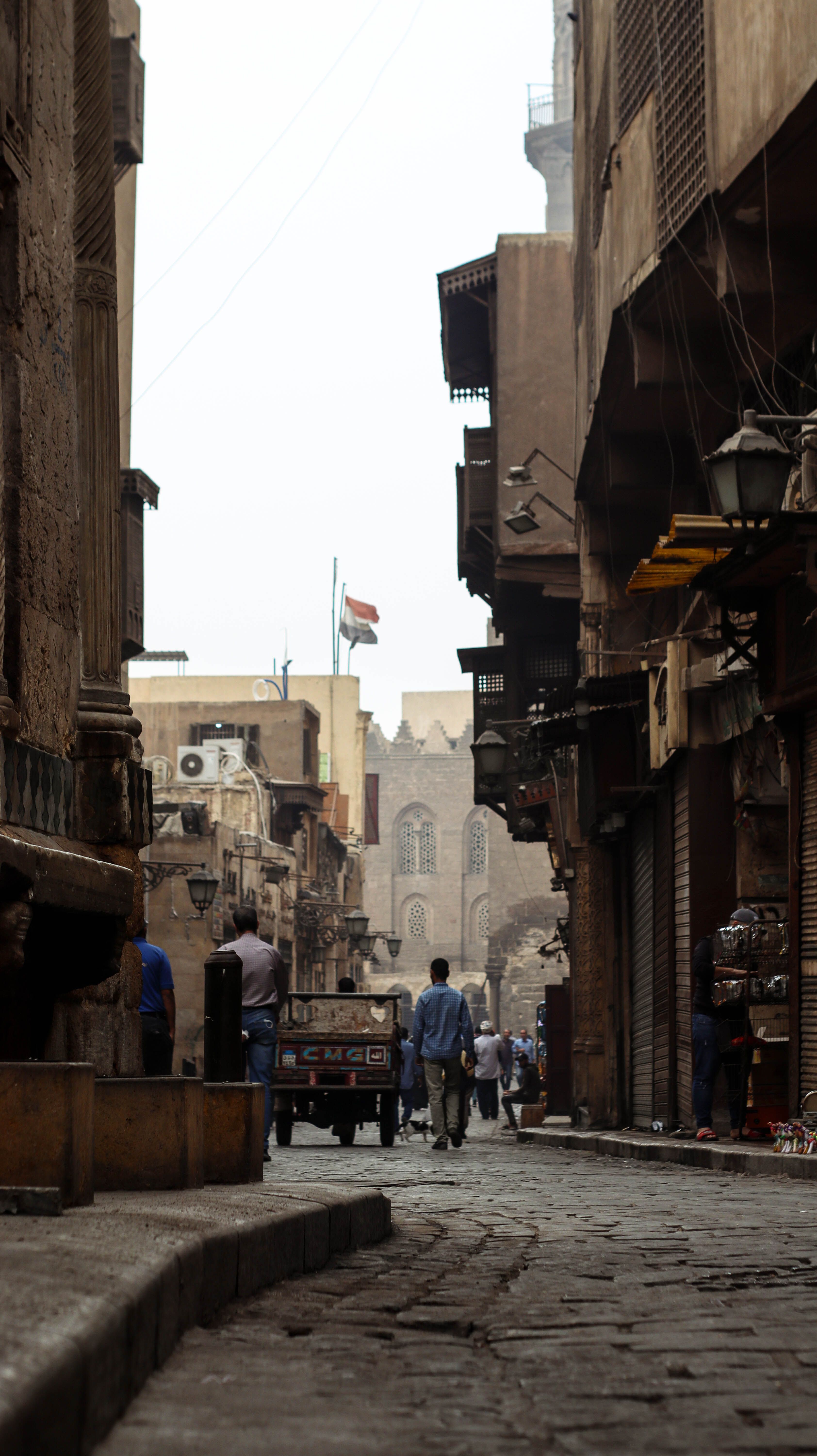 Charming view of people walking through a narrow, paved alleyway in a historical Middle Eastern town.