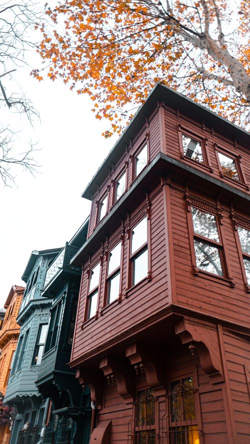 Free Low angle view of ornate wooden buildings showcasing classic architectural design and autumn foliage. Stock Photo