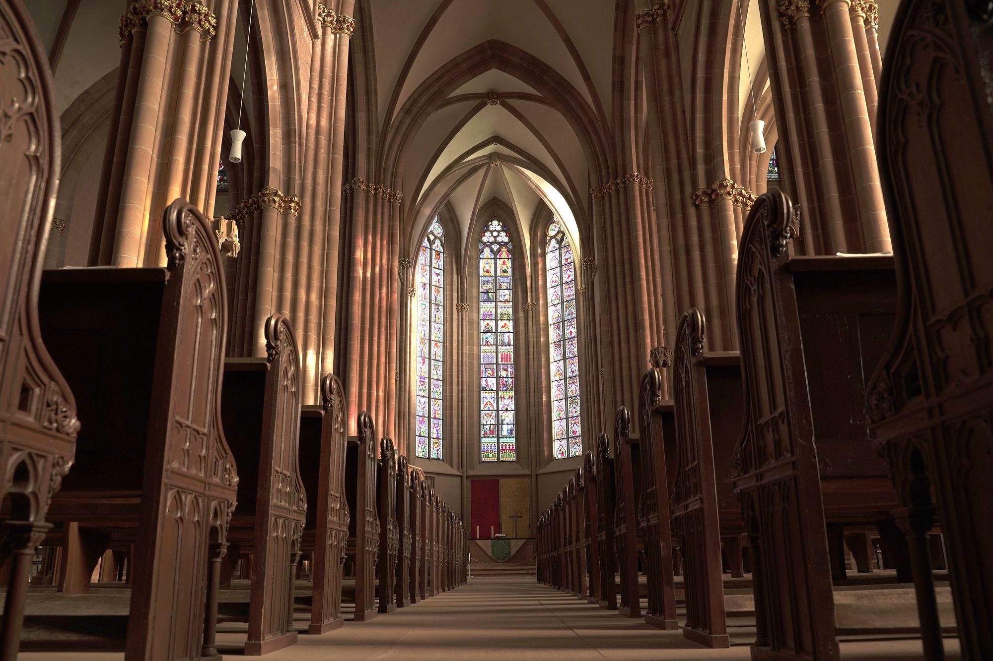 Bancas de madera vacías dentro de una iglesia iluminada por luz natural
