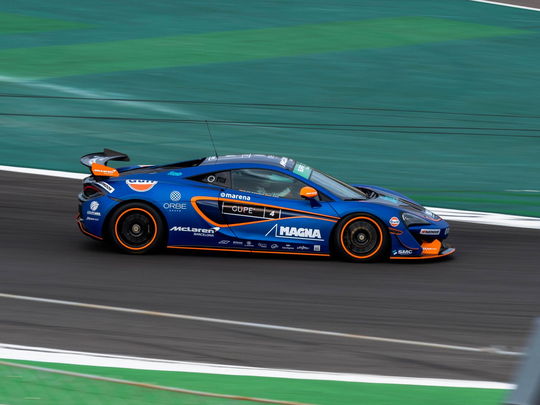 Blue race car speeding on Algarve International Circuit in Portugal, capturing the thrill of motorsport.
