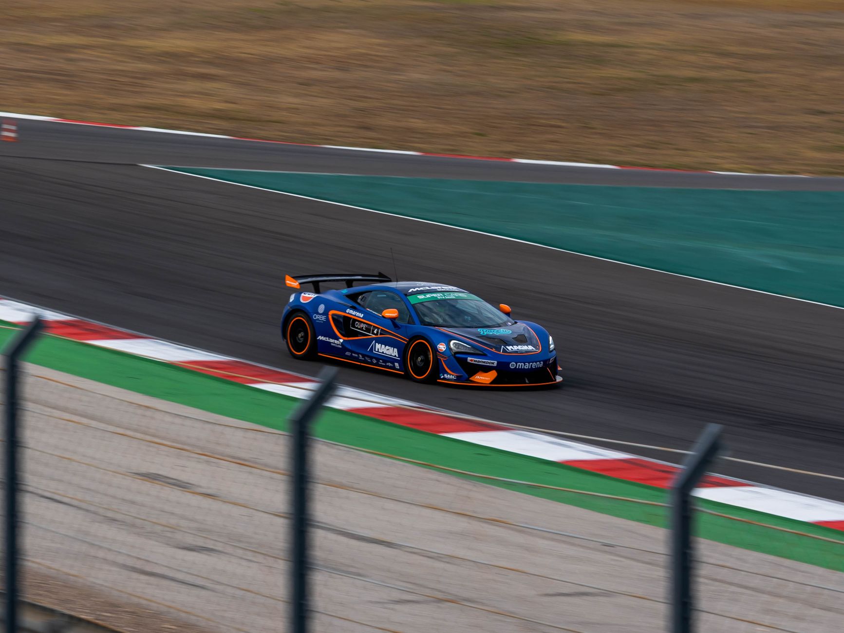 Blue sports car races on Portimão Circuit in Algarve, Portugal.
