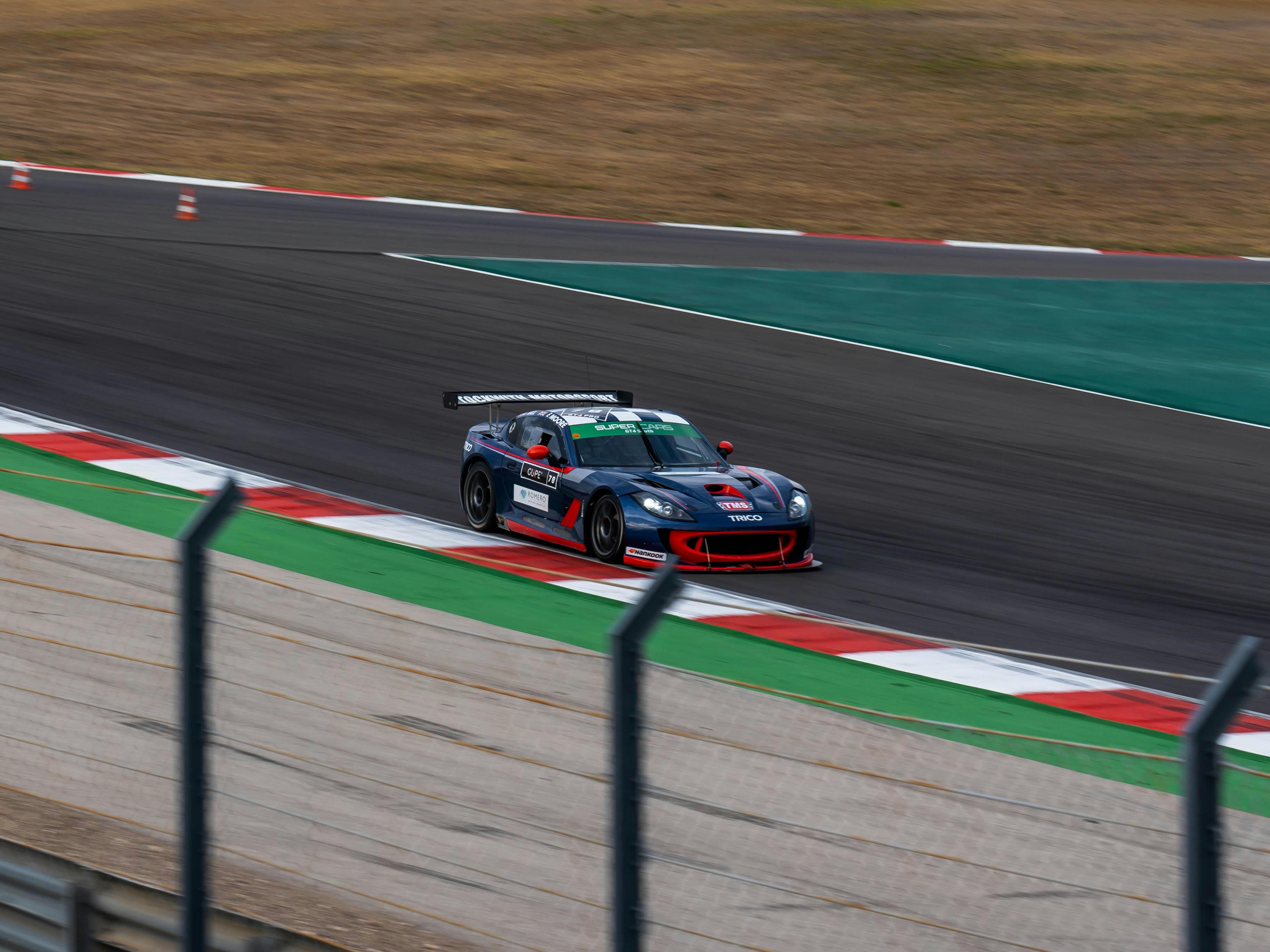 Dynamic shot of a race car speeding on a professional racing track during a motorsport event.